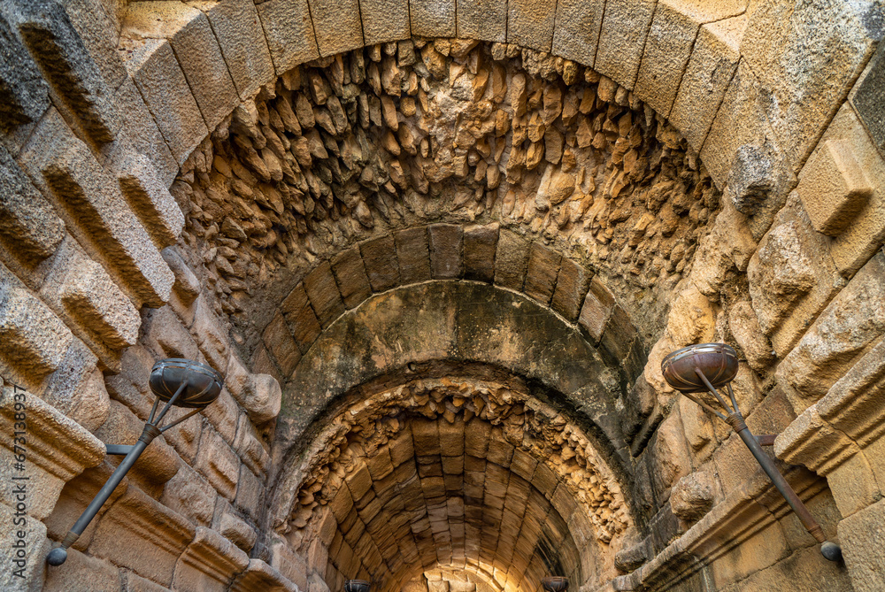 Detail of the vaulted ceiling of stones and rocks with torches on the walls inside one of the entrances to the stands and stage of the ancient Roman Theater of Mérida.