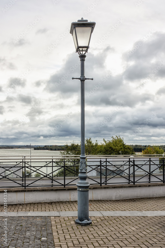 An ancient street lighting lamp on a pole during the day