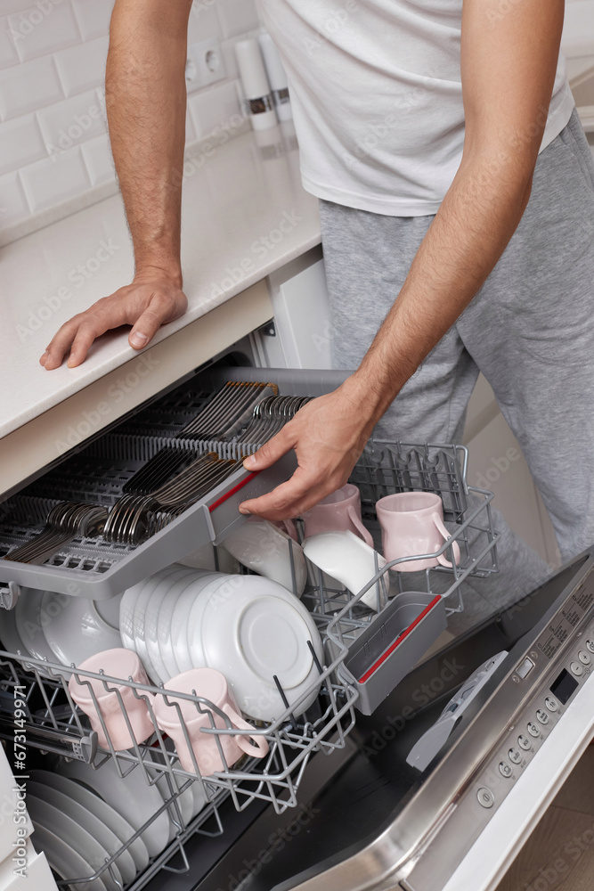 close-up, man unloading dishwasher machine in the kitchen close-up, man unloading dishwasher machine in the kitchen