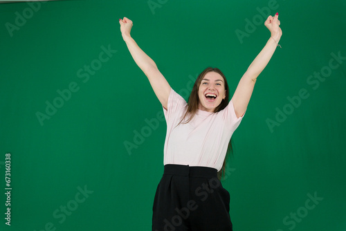 young pretty woman smiling and feeling relaxed, satisfied and carefree, laughing positively and chilling against green background. High quality photo