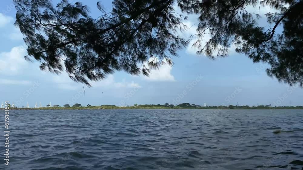 Semarang city marina beach waves during the day. Calm waves on the marina beach and trees on the edge of the marina beach. Semarang city marina beach waves during the day. Calm waves on the marina beach and trees on the edge of the marina beach.