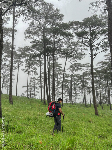 asian young man is trekking on green grass field mountain with t