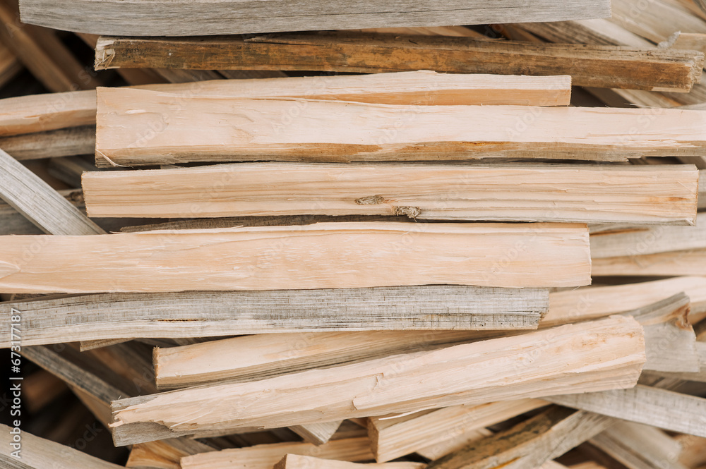 Background, background of a large pile of firewood, chopped thin planks of wood outdoors in the forest. Close-up nature photography, top view.