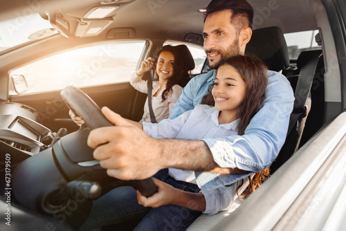 Happy family on a drive, dad at the wheel, daughter co-pilot