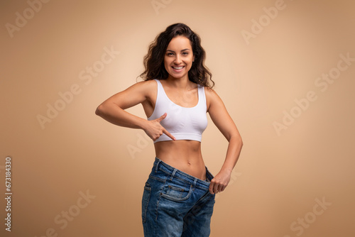 Happy attractive brunette slender millennial woman wearing huge jeans