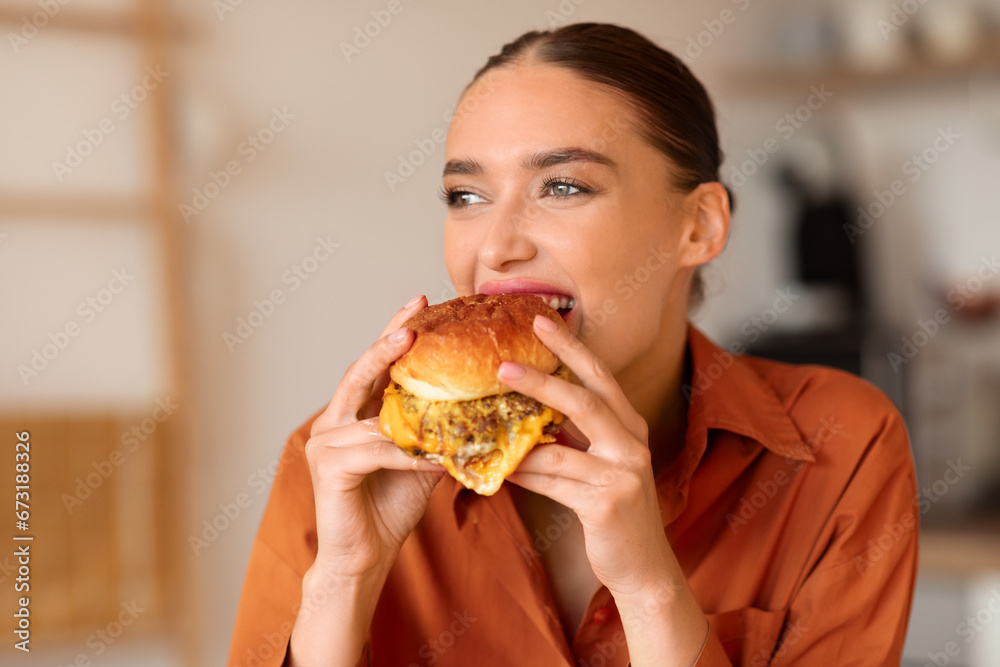 Joyful woman enjoying a bite of her tasty burger Joyful woman enjoying a bite of her tasty burger