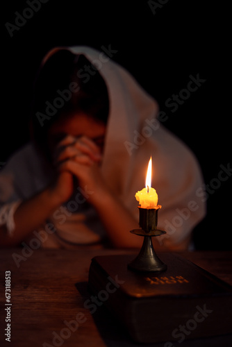 Candle light with blur young girl praying in dark night background. Woman person worship God with faith and belief. religion, christian prayer concept. Christian teenage girl and faith.