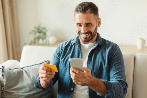 man making purchase using credit card on phone at home