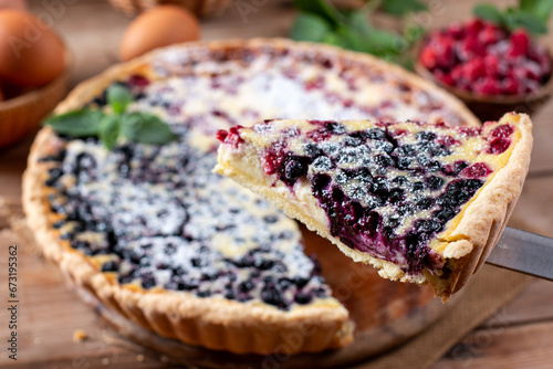 Closeup homemade berry pie with raspberry and blueberry on a wooden table. photo