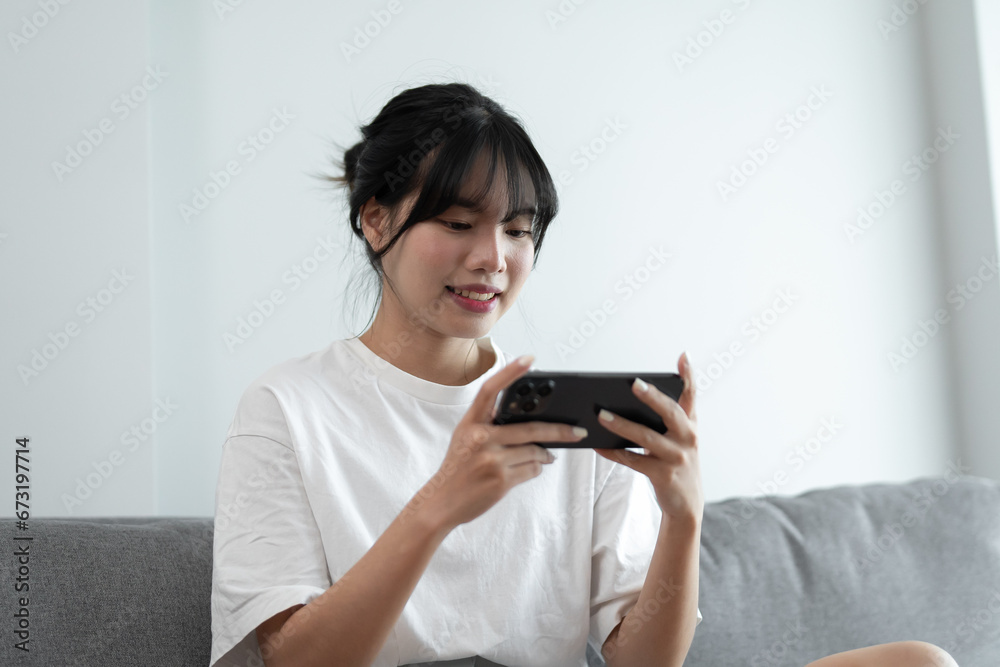 Asian woman playing game on mobile phone. gamer girl playing video games holding Smartphone working mobile devices. cell telephone technology e-commerce concept Asian woman playing game on mobile phone. gamer girl playing video games holding Smartphone working mobile devices. cell telephone technology e-commerce concept