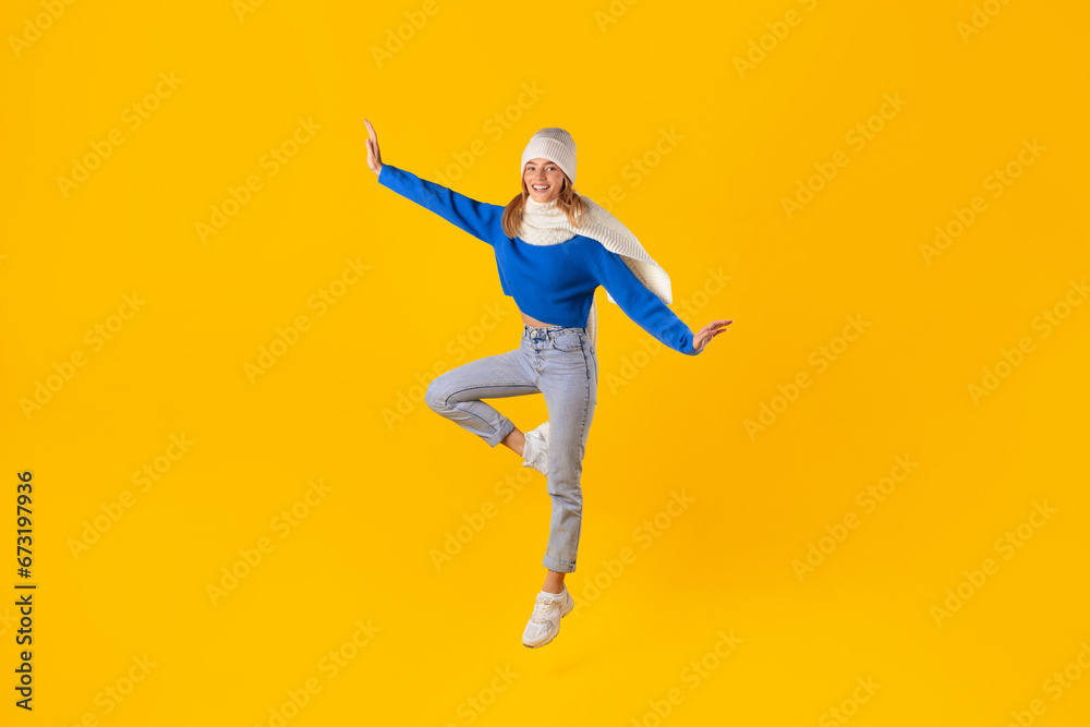 Energetic woman jumping and celebrates winter sales on yellow background