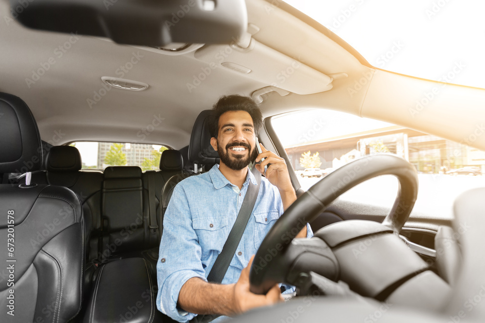 Happy young indian man driver talking on phone