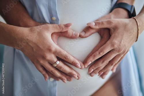 Hands on pregnant mom's belly at heart figure. Family waiting for baby birth during pregnancy
