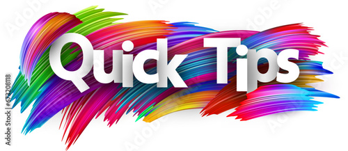 Quick tips paper word sign with colorful spectrum paint brush strokes over white.