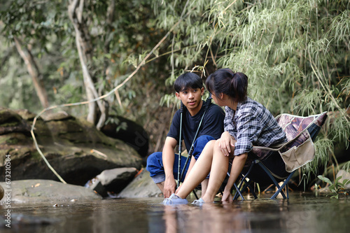 Asian Teenager sitting on a camping chair in the natural stream. while talking.