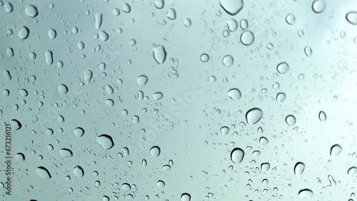 Raindrop on white transparent mirror in rainy day. Falling rain from rainy season sky background. Slow motion footage.