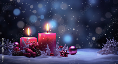 velas de navidad encendidas junto bolas y figuras decorativas  sobre superficie nevada y fondo desenfocado azul 