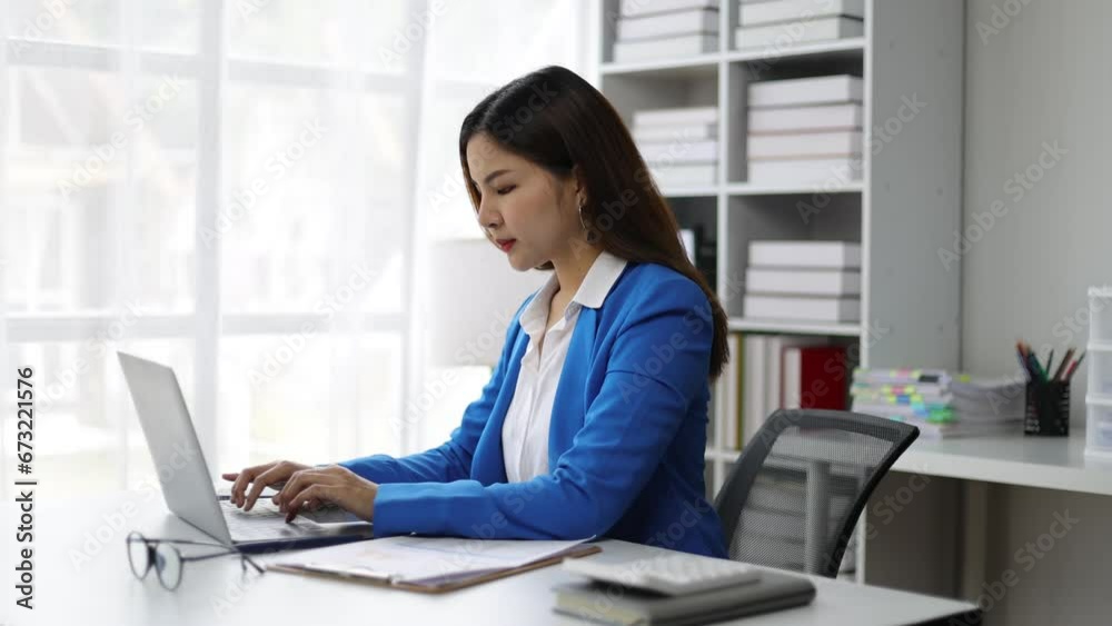 Attractive Asian businesswoman working on documents on laptop on desk in office. Attractive Asian businesswoman working on documents on laptop on desk in office.