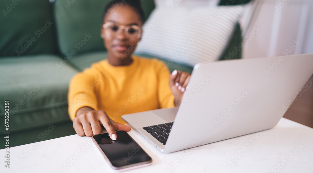 Ethnic woman sitting with laptop and smartphone at home