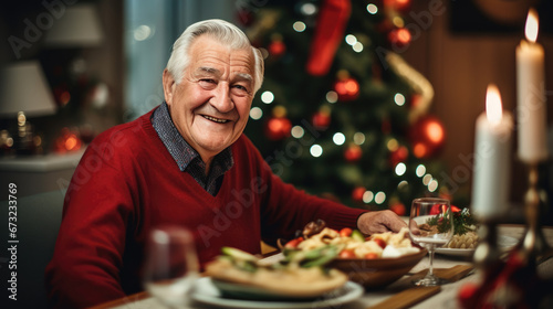 Elderly man smiling at a Christmas dinner table  with a decorated tree in the background and holiday decorations on the table