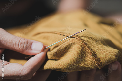 Woman fingers threading a needle