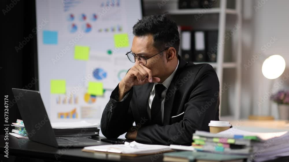Businessman is sleepy while working overtime in the office at night.