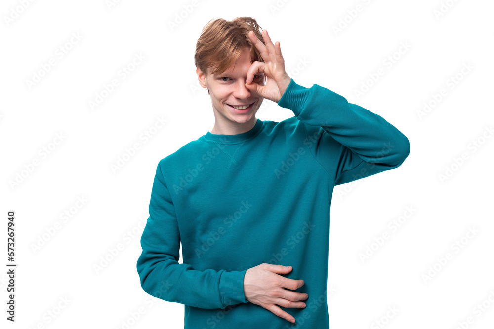 young caucasian student guy with red hair dressed in a blue sweater on a white background with copy space young caucasian student guy with red hair dressed in a blue sweater on a white background with copy space