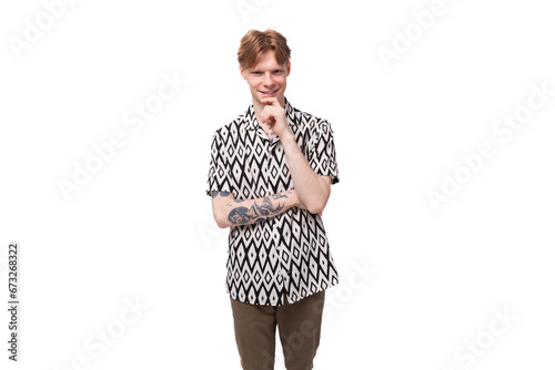 a young smart guy with red hair and a tattoo on his arms is dressed in a short-sleeve shirt thinking about the development of an idea