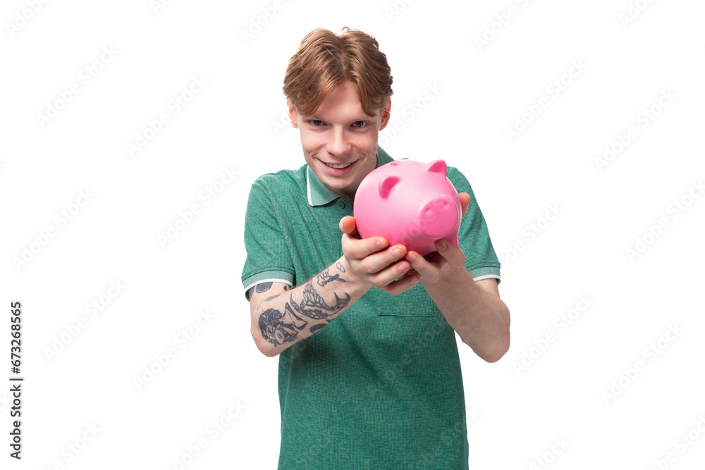 a young red-haired caucasian guy in a green t-shirt is about to empty his piggy bank a young red-haired caucasian guy in a green t-shirt is about to empty his piggy bank