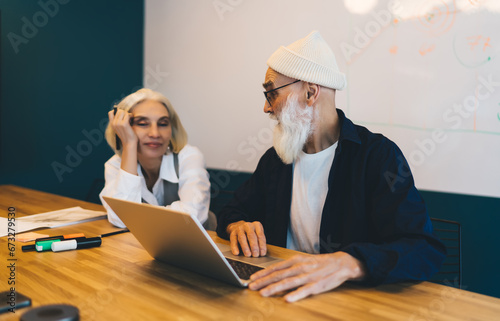 Elderly hipster man and woman working on laptop in office