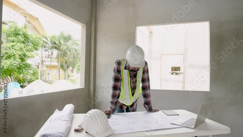 Asian male architect with construction supervisor worker engineer employee Wear white safety helmet. Looking at structural diagram laptop and pointing out points need to be fixed in the building. photo