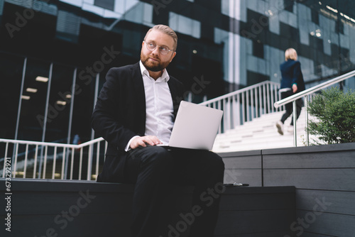 Confident businessman browsing laptop on city street