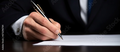 A man s hand is placing his signature on a contract on the designated line photo