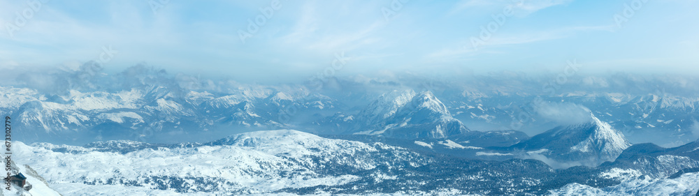 Winter hazy view from Dachstein mountain massif top and house on rocky slope (Austria).