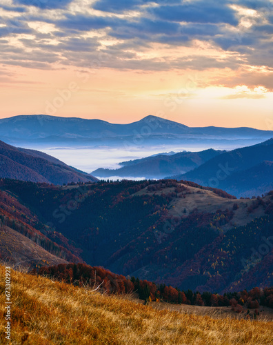 Early dawn in mountains. Autumn morning twilight view with pink sky and mist. © wildman