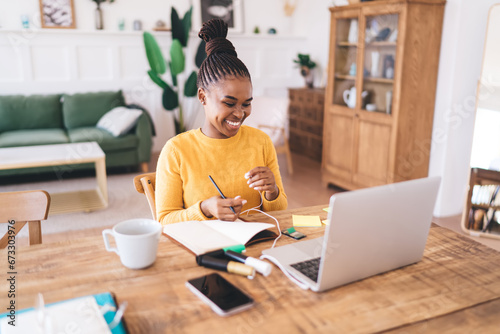 Smiling ethnic woman sitting with laptop in living room