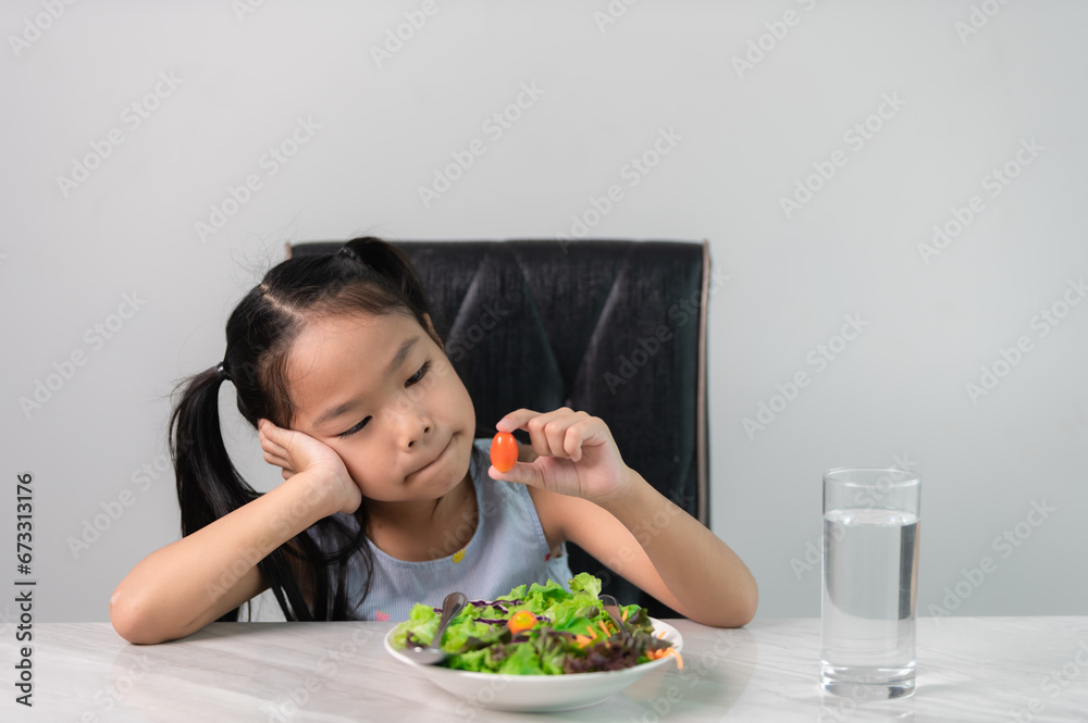 Little asian cute girl refuses to eat healthy vegetables.Nutrition & healthy eating habits for kids concept.Children do not like to eat vegetables. Little asian cute girl refuses to eat healthy vegetables.Nutrition & healthy eating habits for kids concept.Children do not like to eat vegetables.