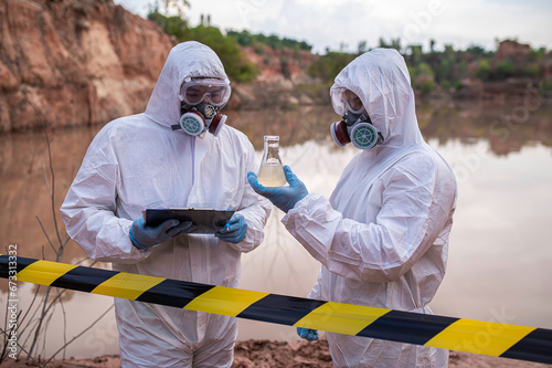 Scientists or biologists wearing protective uniforms working together on water analysis,Environmental engineers inspect water quality in a dangerous area