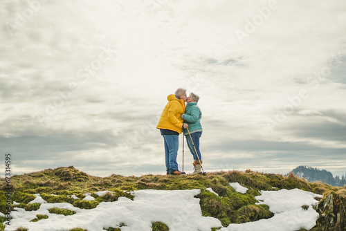 Senior couple having tender moment together at mountain peak during winter trekking day