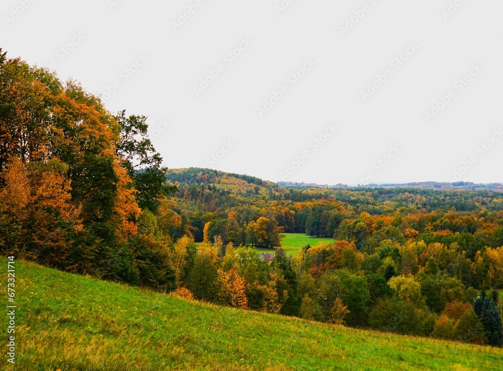 Panorama na roztaczające się góry i las. Przeróżne barwy liści. Jesień widoczna w górach na terenie Czech.
