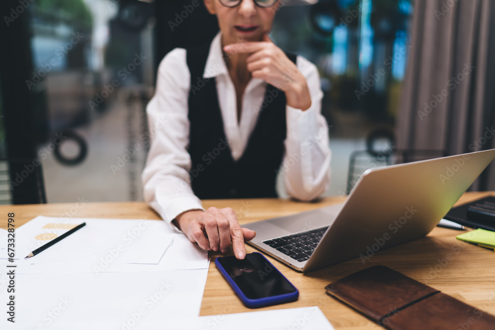 Woman browsing smartphone while sitting at desk in office Woman browsing smartphone while sitting at desk in office