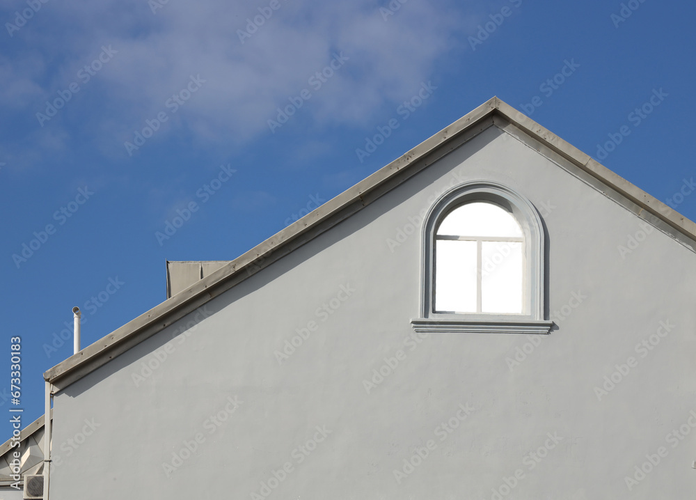 mock up. Exterior white concrete wall of horizontal clapboard siding vintage house with white trim. small pane arched glass window a decorative gable roof. The sky is cloudy. mockup.