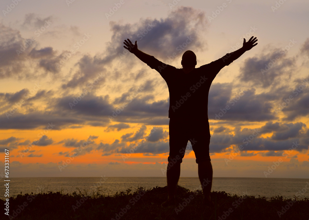 black Silhouette of a man with raised-up arms at the sunset. Silhouette male raised hand in the air with success goal on sunset background. Man standing on top of coast. freedom life concept. hands up