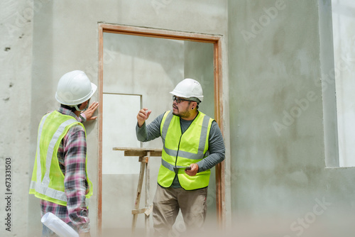Engineer manager foreman young Asian man employee with architects and designers Wear white safety helmet Inspecting the walls of the housing structure Carrying tablet walking around Stay in the house