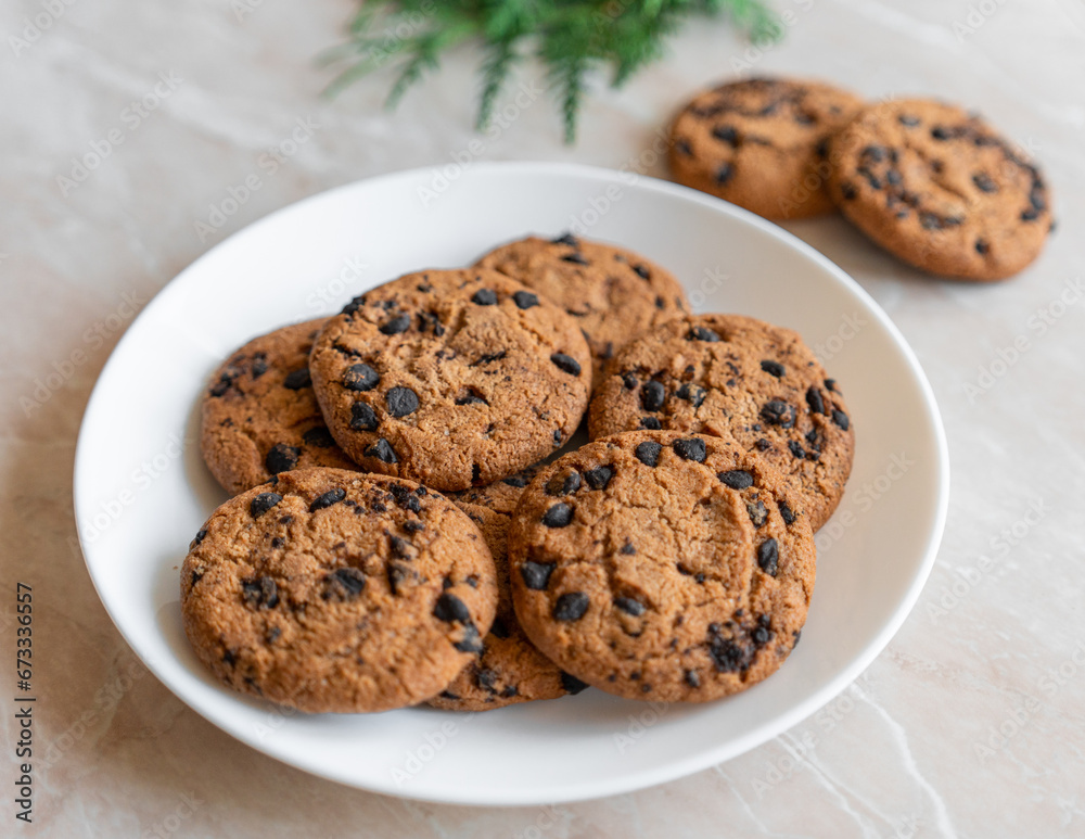 Chocolate cookies on a plate with spruce branches on the table. Dark chocolate cookies on a plate, Christmas cookies chocolate cinnamon sweet dessert holiday treat new year and christmas food Chocolate cookies on a plate with spruce branches on the table. Dark chocolate cookies on a plate, Christmas cookies chocolate cinnamon sweet dessert holiday treat new year and christmas food