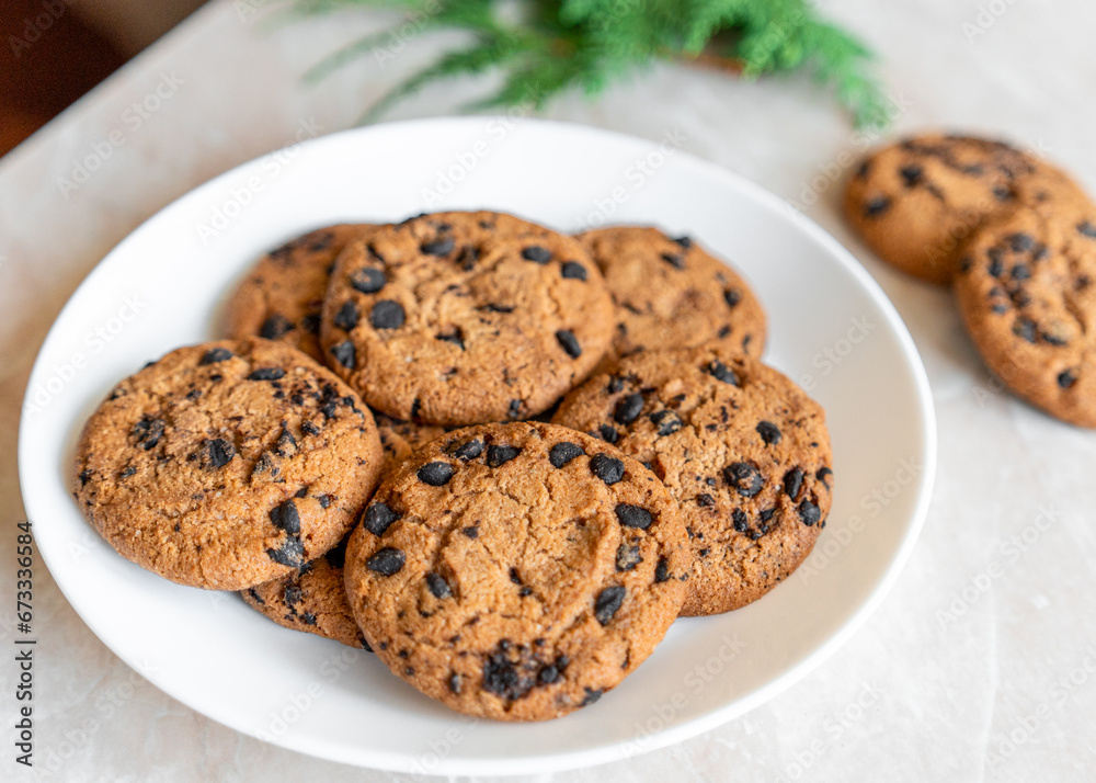 Chocolate cookies on a plate with spruce branches on the table. Dark chocolate cookies on a plate, Christmas cookies chocolate cinnamon sweet dessert holiday treat new year and christmas food Chocolate cookies on a plate with spruce branches on the table. Dark chocolate cookies on a plate, Christmas cookies chocolate cinnamon sweet dessert holiday treat new year and christmas food