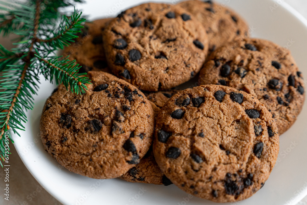 Chocolate cookies on a plate with spruce branches on the table. Dark chocolate cookies on a plate, Christmas cookies chocolate cinnamon sweet dessert holiday treat new year and christmas food Chocolate cookies on a plate with spruce branches on the table. Dark chocolate cookies on a plate, Christmas cookies chocolate cinnamon sweet dessert holiday treat new year and christmas food
