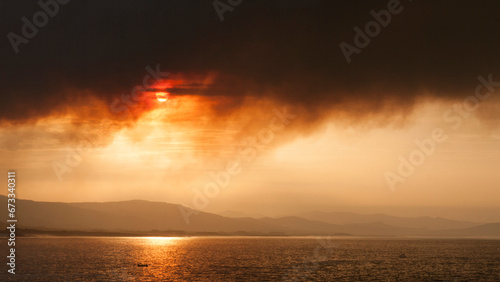 Sol tapado por columna de humo en incendio junto al mar