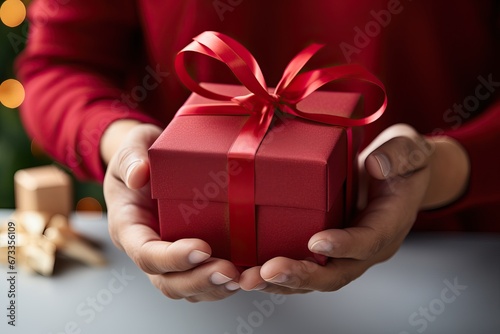 Young man holding gift with red ribbon. Closeup.