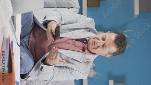 Wallpaper Mural Vertical video of Home office worker old man has phone charging problem, battery runs out. Torontodigital.ca